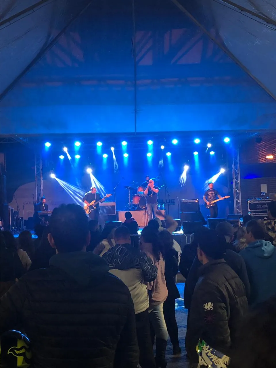 Show da OABoys sob luzes azuis com o público em frente ao palco